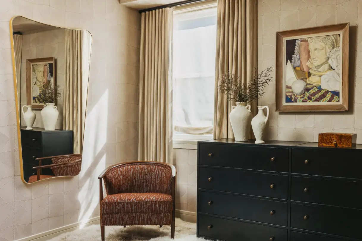 Layered interior with curtains, chair, and textured wall