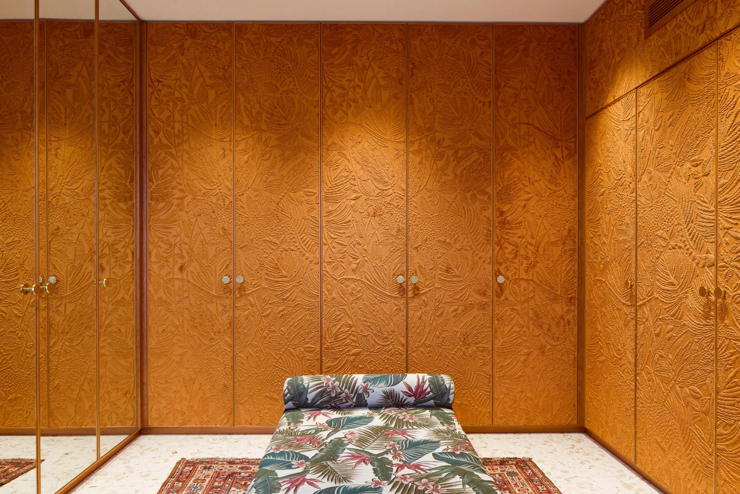 Orange botanical wallcovering and patterned chaise