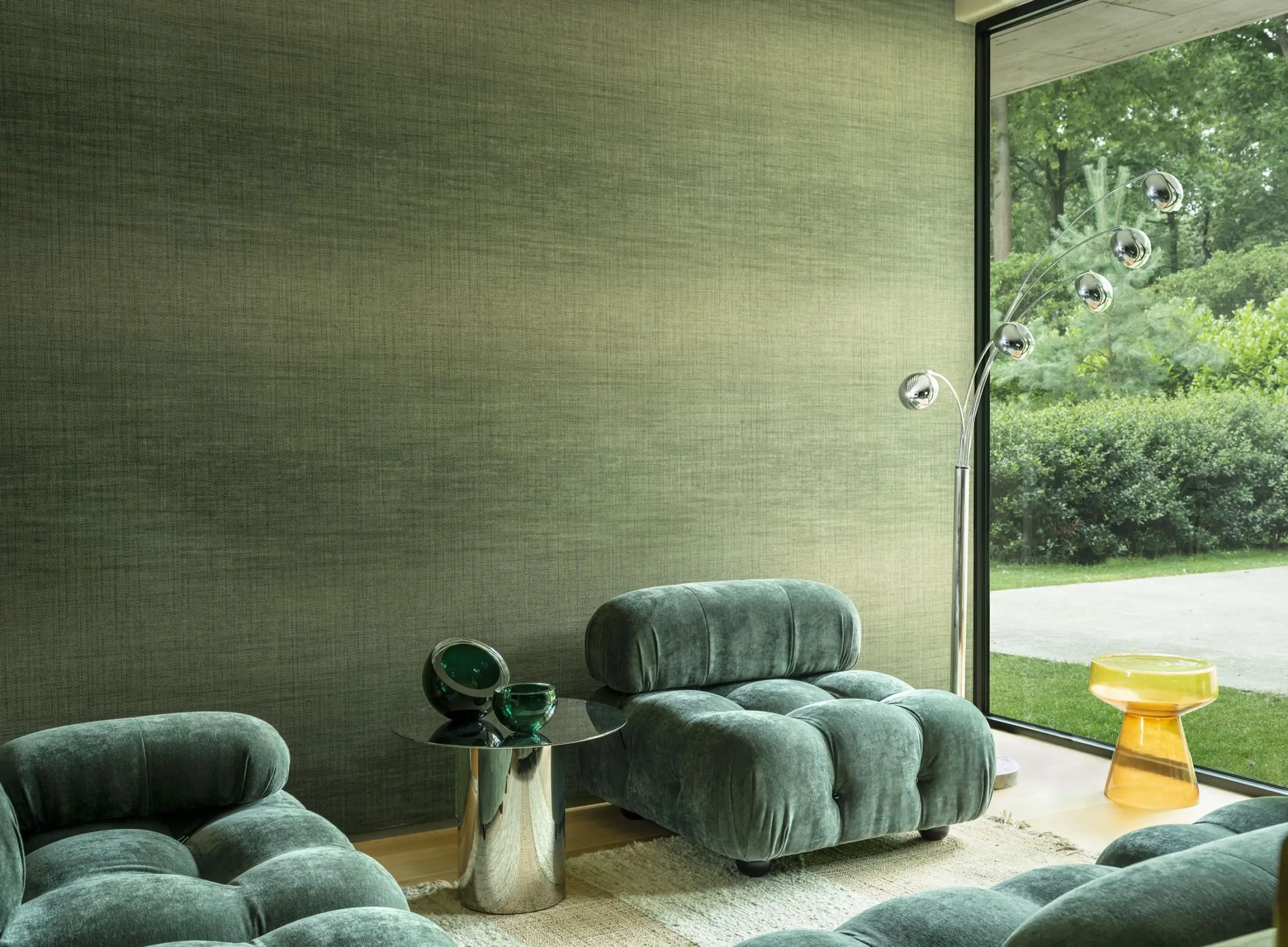 Calm green interior with textured wall, chairs, and garden